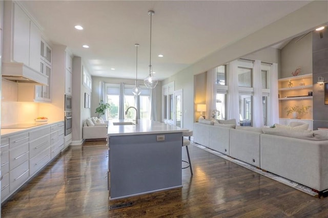 15716 Canterbury St, Overland Park, KS 66085 - kitchen with open floor plan, oven, recessed lighting, dark wood-style floors, and glass insert cabinets