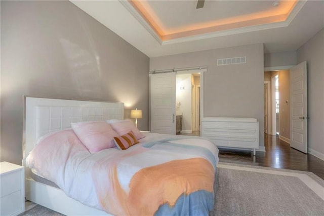 15716 Canterbury St, Overland Park, KS 66085 - bedroom with a tray ceiling, a barn door, wood finished floors, ensuite bathroom, and ceiling fan