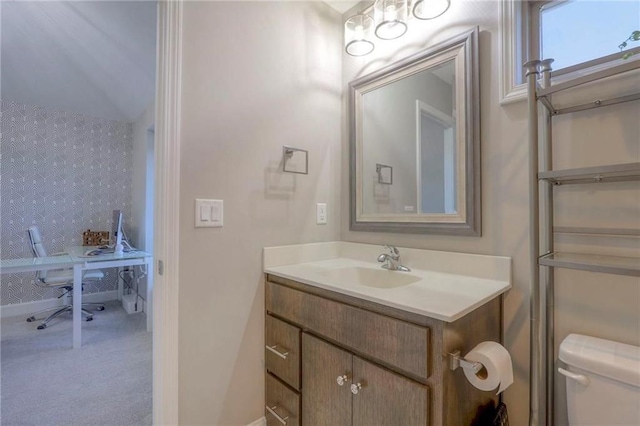 15716 Canterbury St, Overland Park, KS 66085 - half bath featuring wallpapered walls, vanity, and an accent wall