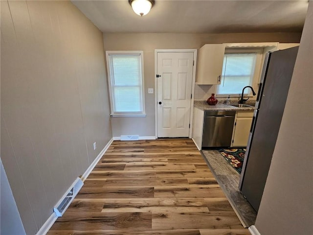 1615 N High St, Independence, MO 64050 - kitchen with appliances with stainless steel finishes, wood finished floors, plenty of natural light, and light stone counters