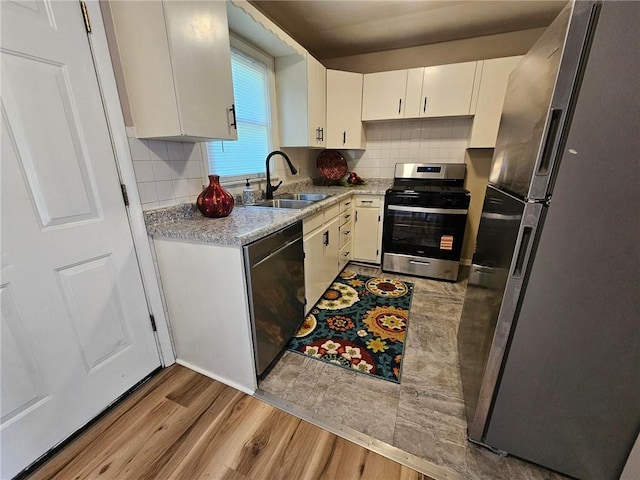 1615 N High St, Independence, MO 64050 - kitchen with stainless steel appliances, light wood-style flooring, white cabinetry, and decorative backsplash
