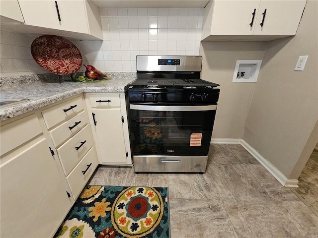 1615 N High St, Independence, MO 64050 - kitchen featuring stainless steel gas range oven, decorative backsplash, light countertops, and white cabinetry
