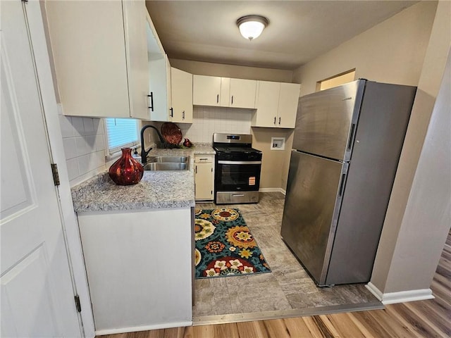 1615 N High St, Independence, MO 64050 - kitchen with appliances with stainless steel finishes, light countertops, light wood-style floors, white cabinetry, and backsplash