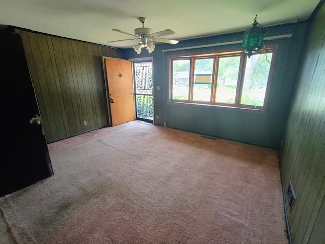 5001 E 41st St, Kansas City, MO 64130 - carpeted empty room featuring wooden walls and a ceiling fan