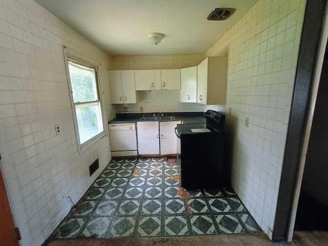 5001 E 41st St, Kansas City, MO 64130 - kitchen featuring white dishwasher, dark countertops, tile walls, white cabinets, and black / electric stove