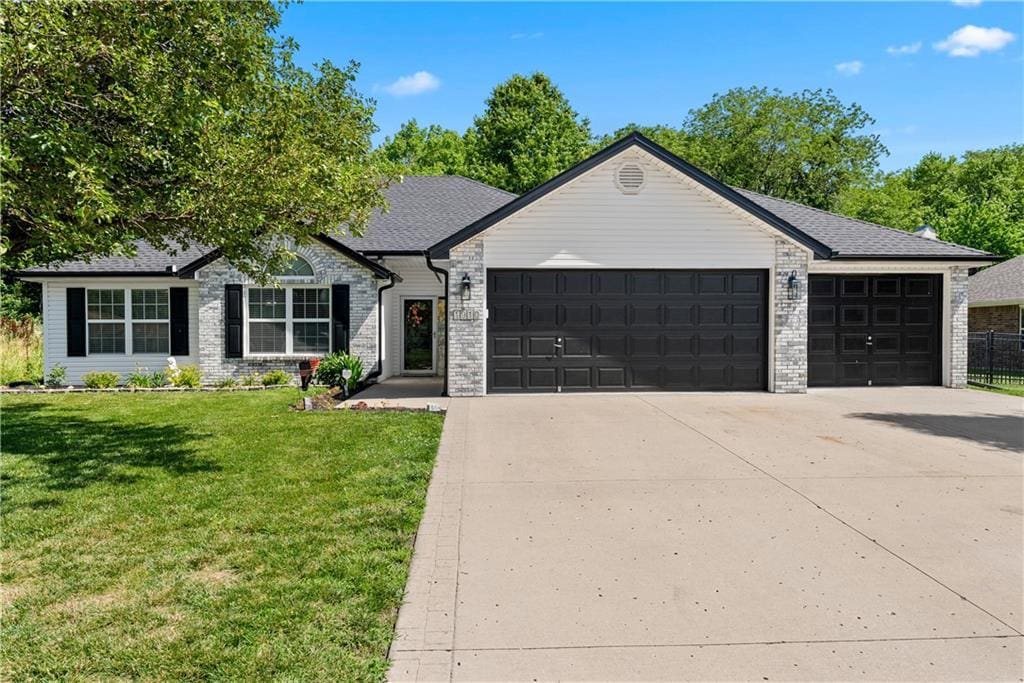 1910 NW Willow Dr, Grain Valley, MO 64029 - view of front of home with concrete driveway, a garage, a front lawn, and brick siding