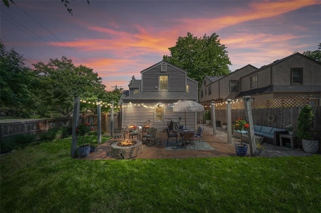 1295 W 71st Ter, Kansas City, MO 64114 - back of house at dusk featuring a patio, an outdoor living space with a fire pit, and a fenced backyard