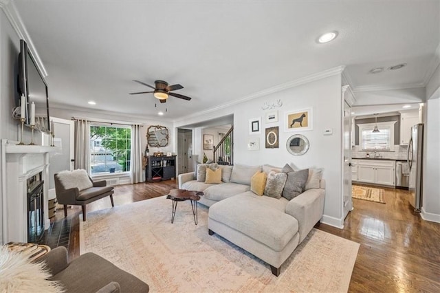 1295 W 71st Ter, Kansas City, MO 64114 - living room featuring a glass covered fireplace, dark wood-style floors, ceiling fan, recessed lighting, and ornamental molding