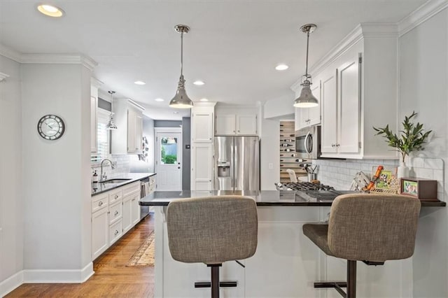 1295 W 71st Ter, Kansas City, MO 64114 - kitchen with stainless steel appliances, a peninsula, backsplash, dark countertops, and white cabinets
