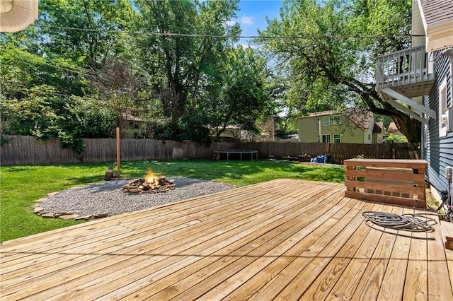 6727 Harvard Ave, Raytown, MO 64133 - wooden terrace with an outdoor fire pit, a fenced backyard, and a trampoline