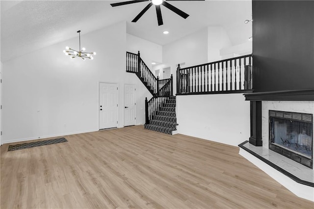 220 NE Dreamweaver Ave, Lees Summit, MO 64086 - unfurnished living room with ceiling fan, wood finished floors, high vaulted ceiling, a fireplace, and a chandelier