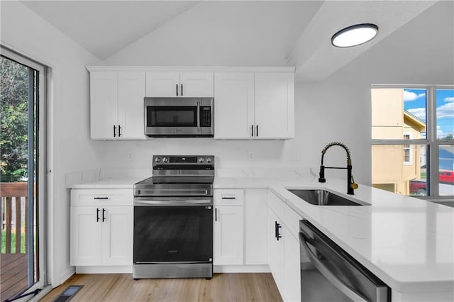 220 NE Dreamweaver Ave, Lees Summit, MO 64086 - kitchen with appliances with stainless steel finishes, vaulted ceiling, a peninsula, light stone countertops, and light wood-style flooring