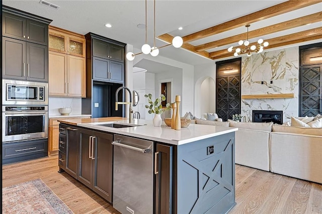 18501 Mohawk Ln, Overland Park, KS 66085 - kitchen featuring appliances with stainless steel finishes, light wood-style floors, a premium fireplace, light countertops, and beamed ceiling