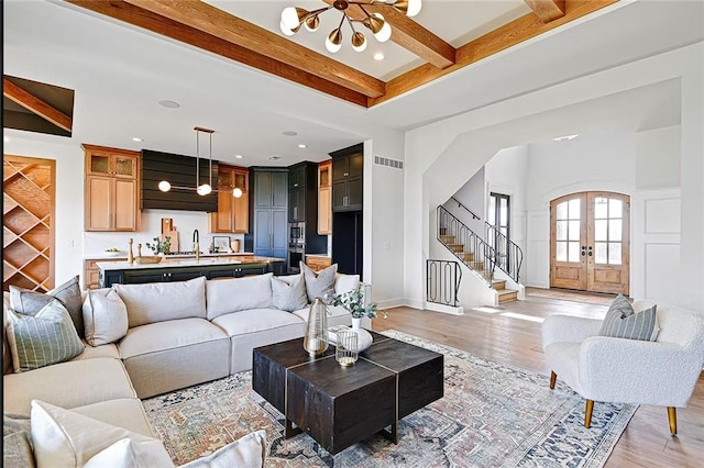 18501 Mohawk Ln, Overland Park, KS 66085 - living area with a chandelier, beam ceiling, stairway, light wood-style floors, and french doors