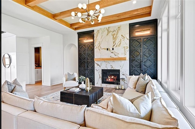 18501 Mohawk Ln, Overland Park, KS 66085 - living room featuring light wood-style floors, a chandelier, a high end fireplace, arched walkways, and beamed ceiling