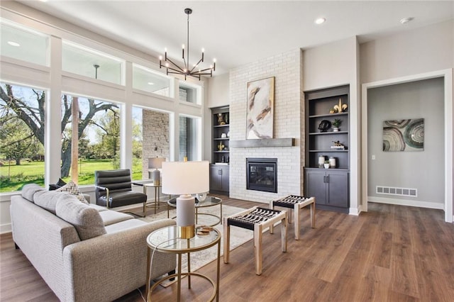 17162 S Heatherwood St, Olathe, KS 66062 - living room featuring wood finished floors, a brick fireplace, a chandelier, recessed lighting, and built in features