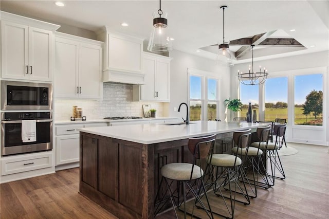 17162 S Heatherwood St, Olathe, KS 66062 - kitchen featuring oven, built in microwave, custom range hood, wood finished floors, and coffered ceiling