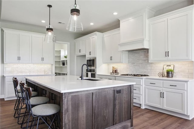 17162 S Heatherwood St, Olathe, KS 66062 - kitchen featuring a kitchen island with sink, dark wood finished floors, tasteful backsplash, stainless steel appliances, and white cabinets