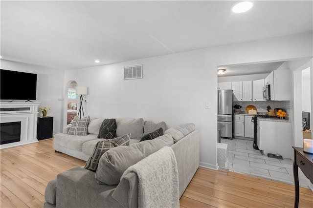 11102 Winchester Ave, Kansas City, MO 64134 - living area with light wood-style flooring, recessed lighting, arched walkways, and a glass covered fireplace