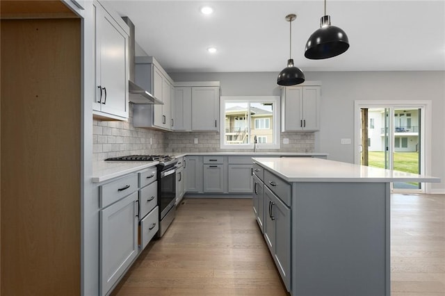 16778 S Twilight Ln, Olathe, KS 66062 - kitchen with gas stove, wall chimney exhaust hood, gray cabinetry, tasteful backsplash, and light wood-type flooring