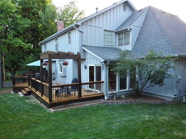 12117 Knox St, Overland Park, KS 66213 - rear view of property featuring a shingled roof, board and batten siding, a wooden deck, a chimney, and a yard