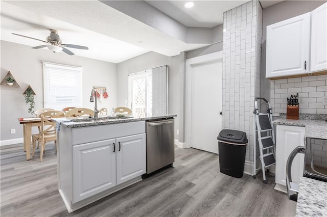3221 E 11th St, Kansas City, MO 64127 - kitchen with stainless steel dishwasher, light wood-style flooring, white cabinetry, and ceiling fan