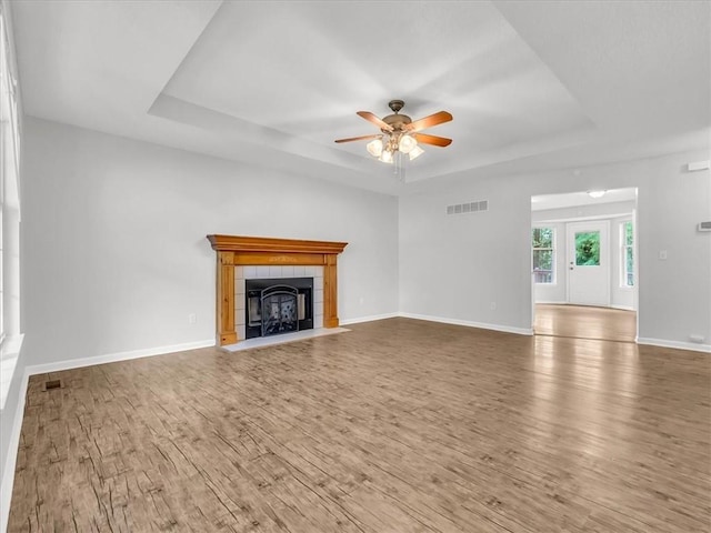1914 S Leslie Dr, Independence, MO 64055 - unfurnished living room with a raised ceiling, a ceiling fan, wood finished floors, and a tiled fireplace