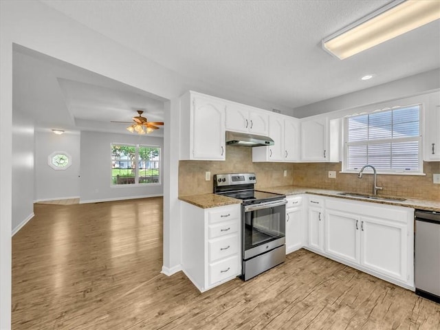 1914 S Leslie Dr, Independence, MO 64055 - kitchen with appliances with stainless steel finishes, under cabinet range hood, light wood-type flooring, light stone countertops, and a textured ceiling