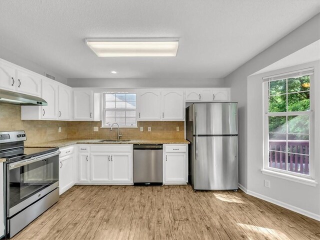1914 S Leslie Dr, Independence, MO 64055 - kitchen with stainless steel appliances, under cabinet range hood, white cabinets, light wood-type flooring, and recessed lighting