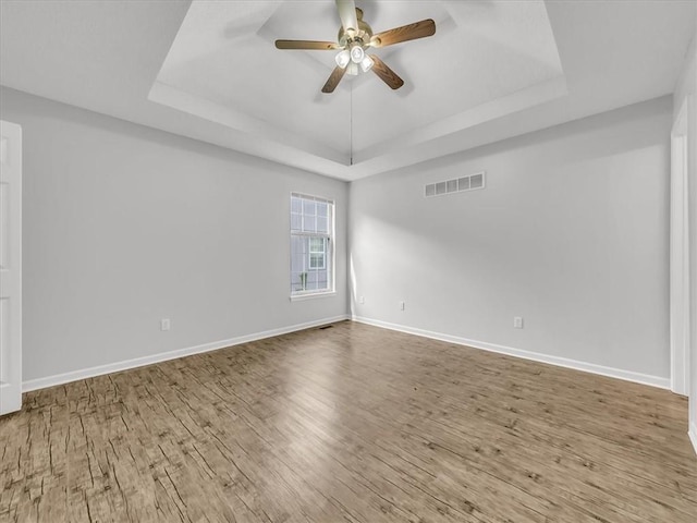 1914 S Leslie Dr, Independence, MO 64055 - empty room featuring a tray ceiling, a ceiling fan, and wood finished floors