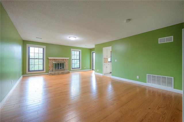 12818 W 110th Ter, Overland Park, KS 66210 - unfurnished living room with a textured ceiling, light wood-type flooring, and a glass covered fireplace