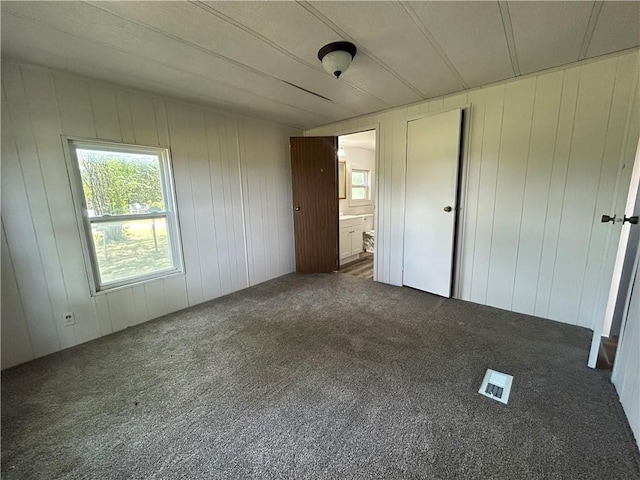 2587 Crk 2200, Caney, KS 67333 - unfurnished bedroom featuring carpet flooring, multiple windows, wood walls, and ensuite bath