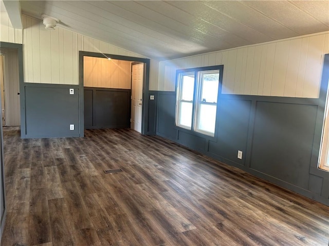2587 Crk 2200, Caney, KS 67333 - unfurnished room with vaulted ceiling, dark wood-style flooring, a decorative wall, and wood walls