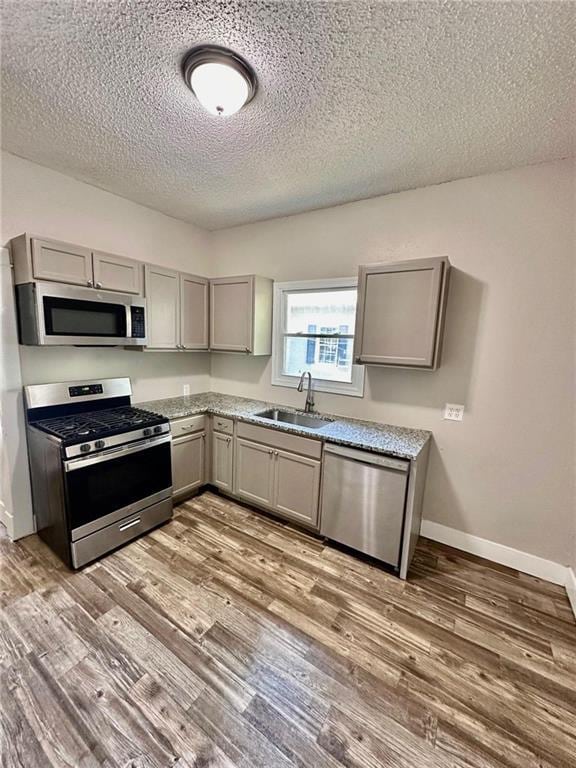 537 S Brookside Ave, Independence, MO 64053 - kitchen featuring appliances with stainless steel finishes, gray cabinets, a textured ceiling, and wood finished floors