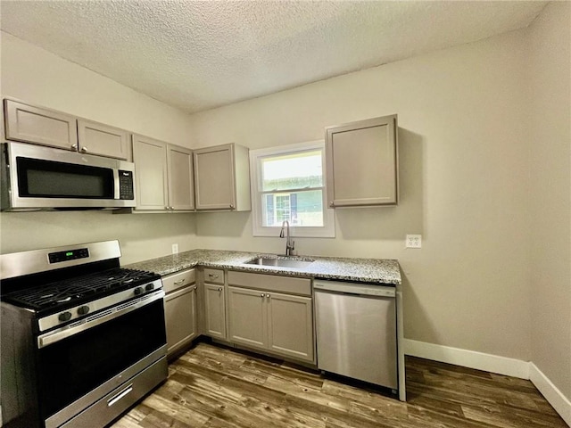 537 S Brookside Ave, Independence, MO 64053 - kitchen featuring appliances with stainless steel finishes, gray cabinetry, dark wood-style flooring, and a textured ceiling