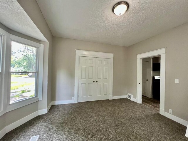 537 S Brookside Ave, Independence, MO 64053 - unfurnished bedroom featuring a textured ceiling, dark carpet, and a closet