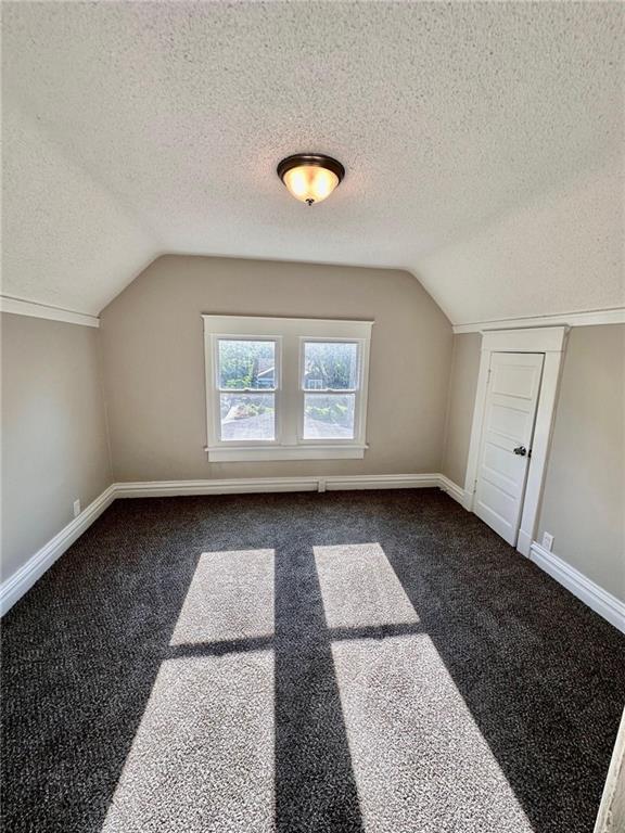 537 S Brookside Ave, Independence, MO 64053 - bonus room featuring a textured ceiling, vaulted ceiling, and dark colored carpet
