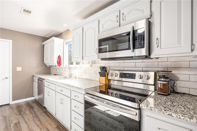 1433 Haskell Rd, Williamsburg, KS 66095 - kitchen with appliances with stainless steel finishes, white cabinets, tasteful backsplash, light stone countertops, and recessed lighting