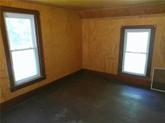 1022 Sycamore St, Humboldt, KS 66748 - empty room featuring healthy amount of natural light, wood ceiling, wooden walls, and dark wood-style flooring
