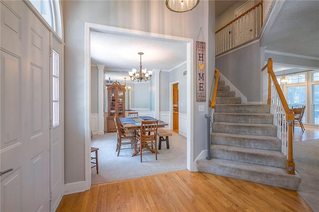 11580 S Skyview Ln, Olathe, KS 66061 - carpeted dining room with crown molding, stairway, a chandelier, wood finished floors, and a decorative wall