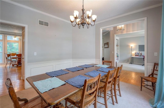 11580 S Skyview Ln, Olathe, KS 66061 - dining space with a chandelier, ornamental molding, light carpet, wainscoting, and a textured ceiling