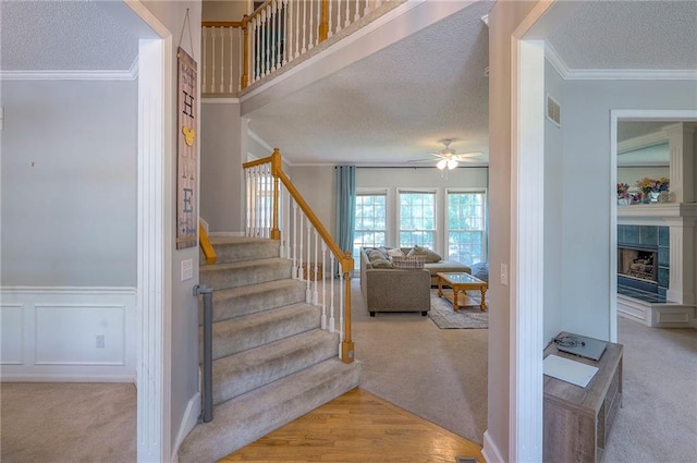 11580 S Skyview Ln, Olathe, KS 66061 - stairs with ornamental molding, carpet, a textured ceiling, ceiling fan, and a tiled fireplace