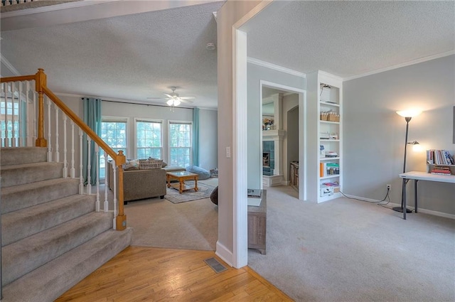 11580 S Skyview Ln, Olathe, KS 66061 - stairs featuring a textured ceiling, ornamental molding, a ceiling fan, carpet flooring, and a tile fireplace