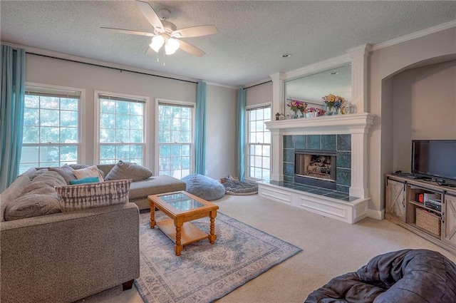 11580 S Skyview Ln, Olathe, KS 66061 - living room featuring a textured ceiling, ornamental molding, ceiling fan, a tiled fireplace, and light colored carpet