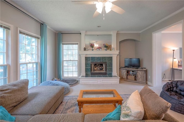 11580 S Skyview Ln, Olathe, KS 66061 - carpeted living area with ornamental molding, a tiled fireplace, a ceiling fan, and a textured ceiling