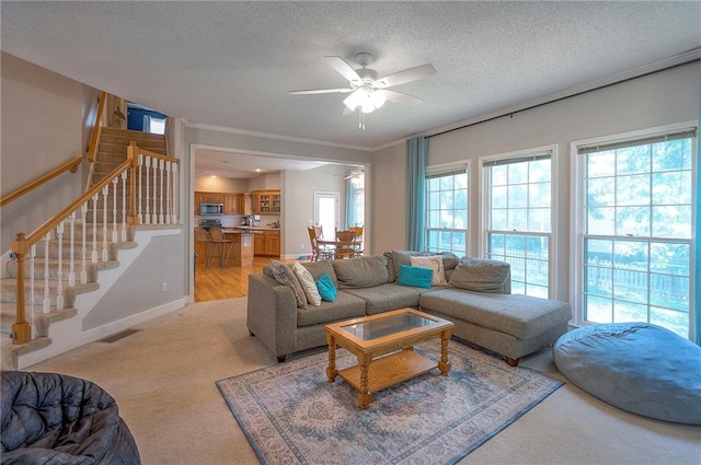 11580 S Skyview Ln, Olathe, KS 66061 - living area with a ceiling fan, stairway, a textured ceiling, light carpet, and crown molding