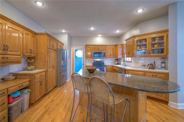 11580 S Skyview Ln, Olathe, KS 66061 - kitchen featuring stainless steel appliances, a breakfast bar, decorative backsplash, a textured ceiling, and light wood-style floors