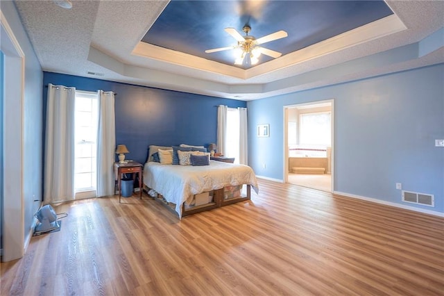 11580 S Skyview Ln, Olathe, KS 66061 - bedroom with a tray ceiling, multiple windows, wood finished floors, and connected bathroom