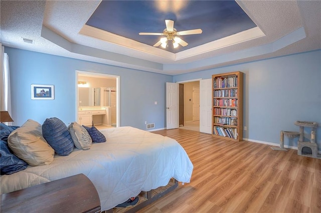 11580 S Skyview Ln, Olathe, KS 66061 - bedroom featuring a tray ceiling, wood finished floors, ensuite bath, and a ceiling fan