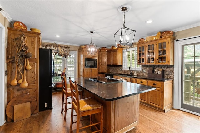 200 NE Oak Tree Cir, Lees Summit, MO 64086 - kitchen featuring black appliances, crown molding, brown cabinets, light wood-style floors, and backsplash
